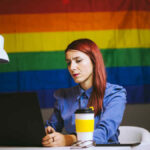Gays at work series - woman working with pride flag behind her