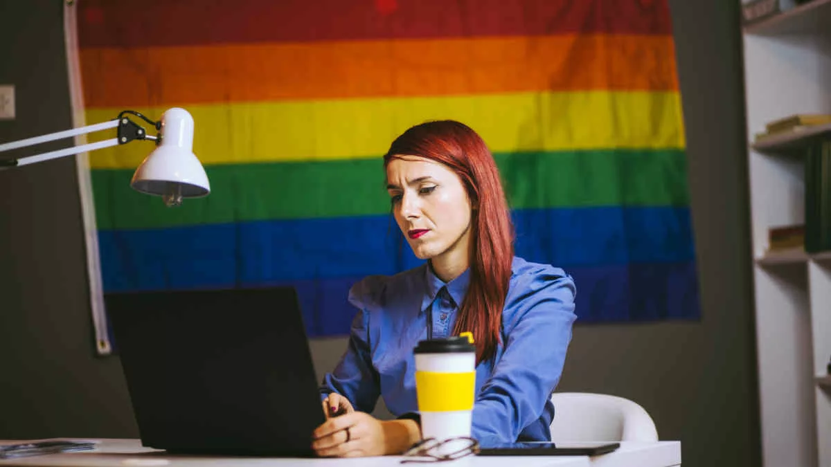Gays at work series - woman working with pride flag behind her